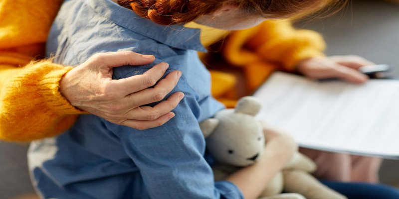 child holding teddy bear with counsellor