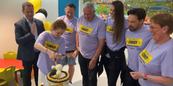 Children's Ward patient Kayla cutting a cake, surrounded by her Dad, members of the Convoy team and ISLHD Chief Executive