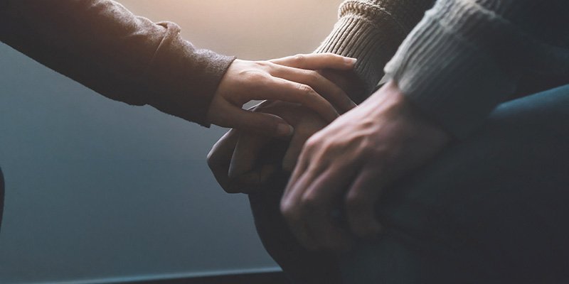 Image of a hand reaching out to someone with their hands on their knees