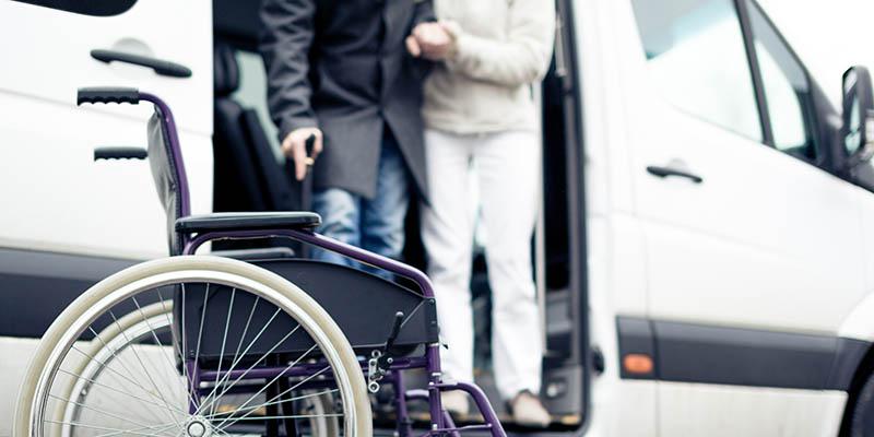 Image of people exiting a transport vehicle with a wheelchair waiting for them. 