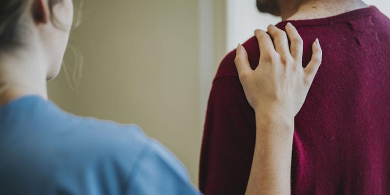 A reassuring hand on a person's shoulder