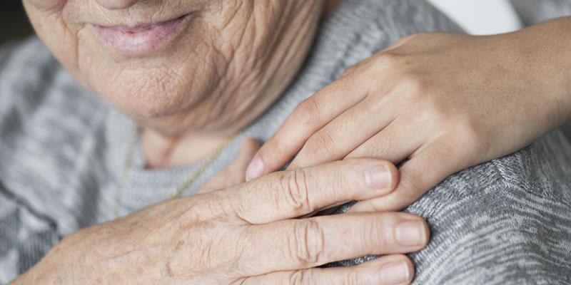 An elderly man with a comforting hand on his shoulder