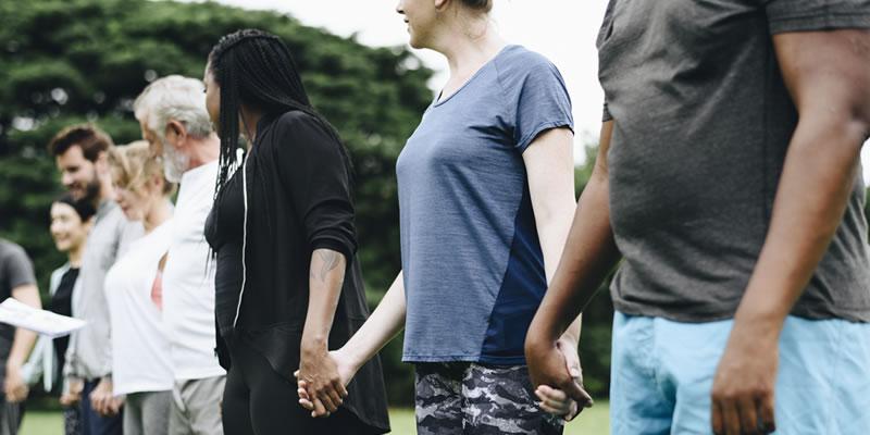 Image of a group of adults standing in a row holding hands