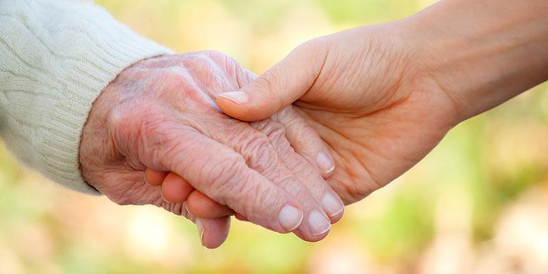 Image of a person holding an elderly patient's hand