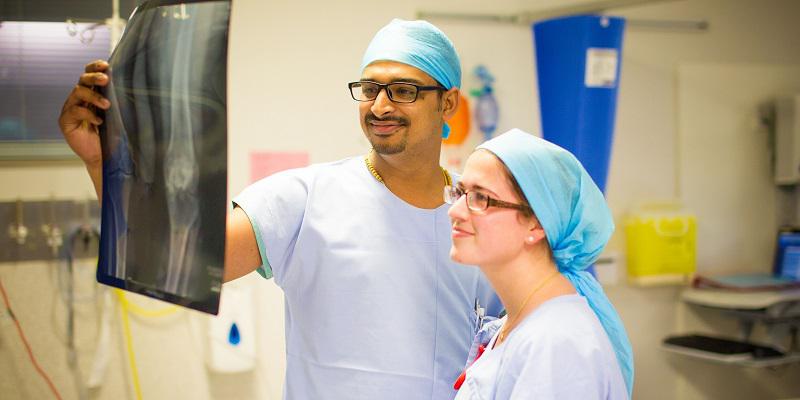 Two doctors in surgical scrubs reviewing an x-ray