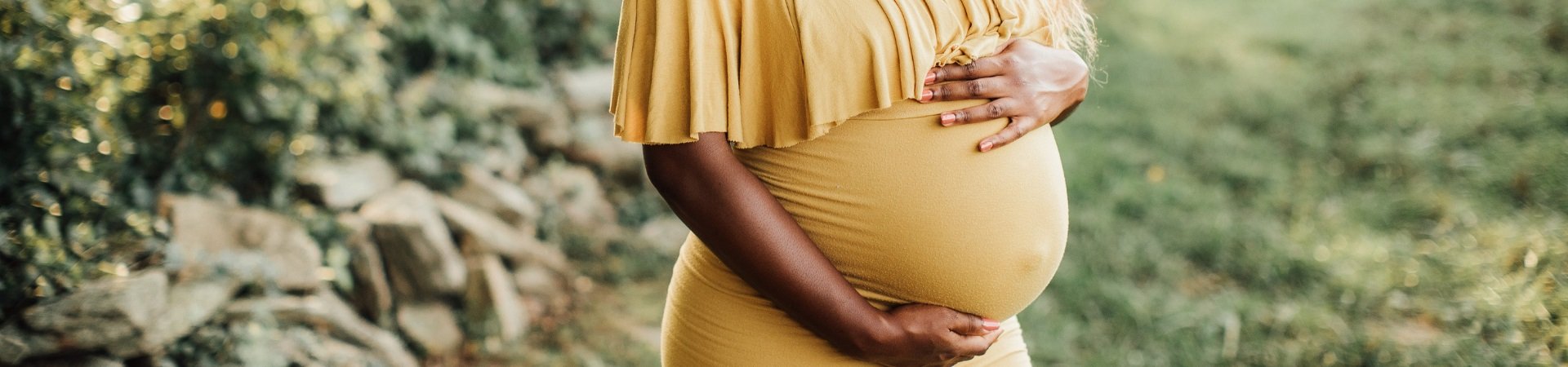 Header image pregnant woman in yellow dress holding belly